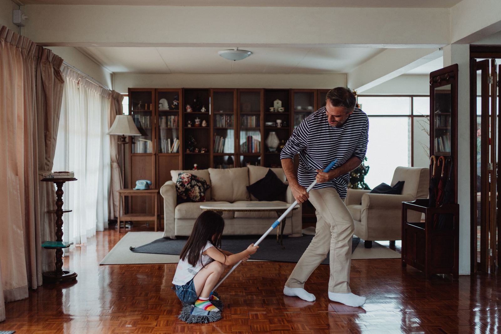 A person vacuuming the transition between a rug and hardwood floor