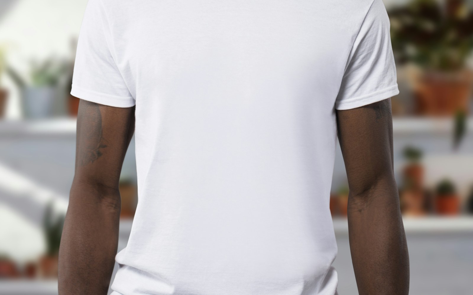 A woman wearing a simple white T-shirt in a bright everyday bedroom